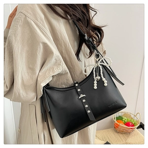 Detail of black croissant bag with silver buckle and pearl bow charm accessory