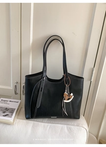 Detail of black tote bag with white contrast stitching and a decorative horse charm