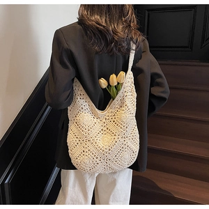 Detail of cream crochet shoulder bag showing floral knit pattern and hollow texture