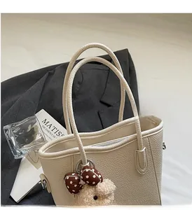 Detail of off-white lychee grain leather bucket bag with a cute plush bear charm
