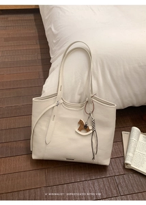Close-up of off-white tote bag with wooden horse charm and tassel on soft home background