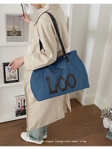 Λεπτομέρεια τσάντας tote denim με μαύρες δερμάτινες λαβές και τυπωμένη τέχνη