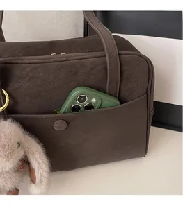 Close-up of deep brown suede tote bag with front pocket and pink bunny plush keychain