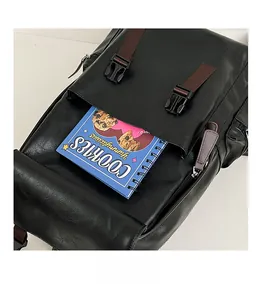 Close-up of black PU leather backpack showing front flap pocket with brown webbing strap buckle