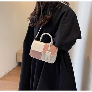 Vista lateral del bolso bandolera bicolor en crema y rosa palo llevado por una modelo
