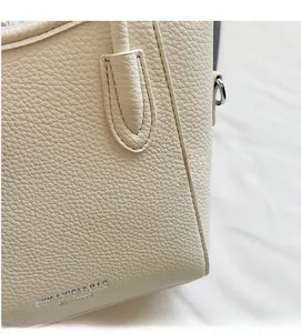 Close-up of beige lychee grain leather texture with stitching and metal hardware details