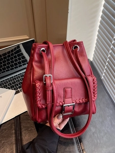 Sac seau bordeaux élégant avec texture cuir et détails tressés uniques sur les bords