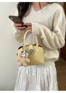 Detail of light yellow retro handbag with a cute plush bear charm and metal twist lock