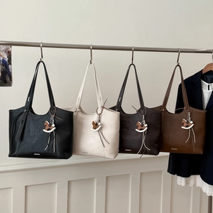 Detail of four colorful tote bags with metal logo plates and wooden rocking horse charms