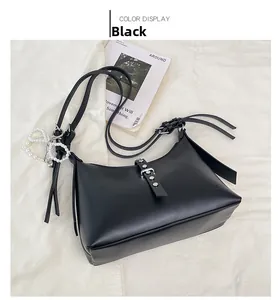Detail of black matte leather dumpling bag with silver buckles and pearl strap decor