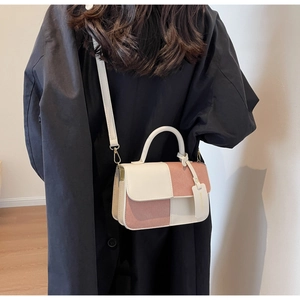 Detailaufnahme einer zweifarbigen Tasche aus beigem Leder und rosa Wildleder am Modell