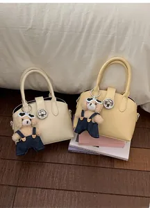 Detail of retro shell handbags in cream and yellow with a cute teddy bear charm accessory