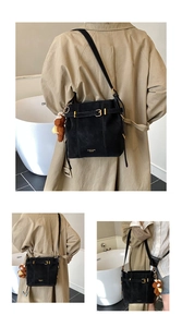 Detail der schwarzen matten Beuteltasche mit goldenen Details und Bärenanhänger