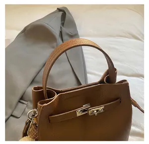 Dettaglio borsa in pelle marrone con motivo litchi, chiusura girevole argento e manico
