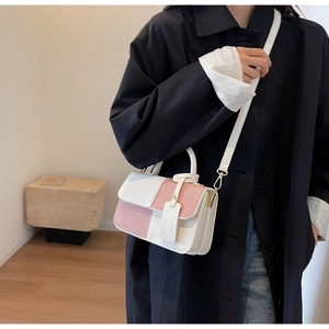 Detail of cream and dusty pink color-block handbag worn with a dark winter coat