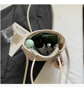 Detail showing the large interior capacity of this cream bucket bag on a grey blazer
