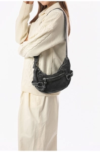 Détail du sac croissant en denim délavé avec fermetures éclair argentées et look rétro