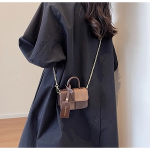 Detail of color-block mini bag in brown leather with gold chain and fashion tag