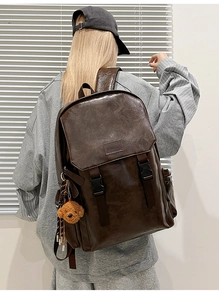 Detail of vintage brown PU leather backpack with flap closure and cute bear pendant