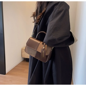 Detail of color-block crossbody bag featuring mixed textures and fashion tag
