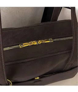 Detail view of smooth golden double zippers and textured leather on dark brown tote bag