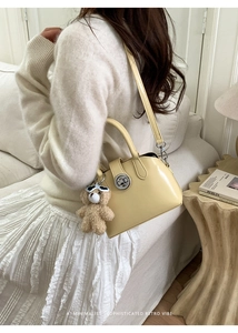 Cream-colored polished PU leather handbag with a plush bear charm and metallic clasp