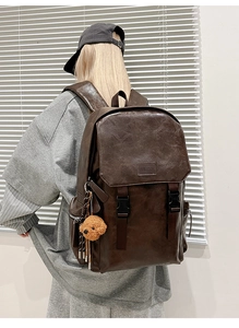 Detail of vintage brown PU leather backpack with buckle closure and plush bear pendant