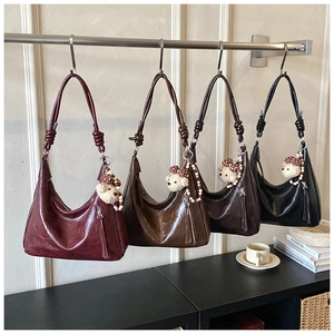 Détail de sacs hobo avec bandoulières nouées et charms d'ours en peluche en quatre couleurs