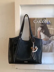 Minimalist black leather tote bag with white contrast stitching and horse pendant