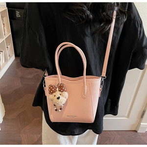 Pink grain leather bucket bag featuring a cute bear charm and adjustable shoulder strap
