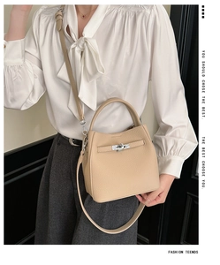 Detail of beige lychee pattern leather handbag featuring a silver twist lock and strap