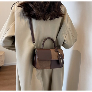 Detail of a brown patchwork leather handbag with fashion tag shown on a beige coat
