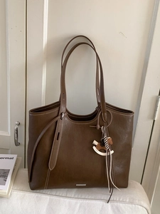Brown faux leather tote bag with contrast stitching and a wooden rocking horse charm