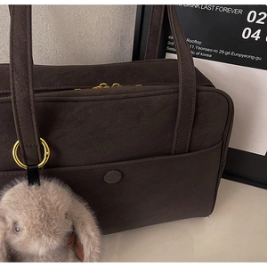 Detail view of coffee brown suede tote bag with plush bunny charm and golden zipper