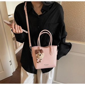 Detail of pink lychee leather bucket bag with adjustable strap and cute plush bear charm