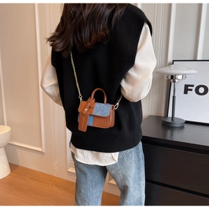 Detail of color-block mini bag with denim and leather texture worn by a model