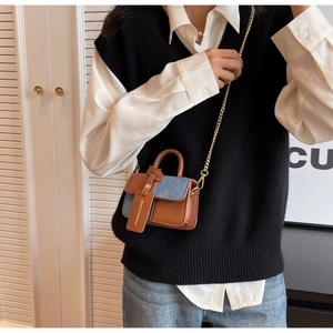 Detail of mini color-block handbag showing brown leather and blue denim texture with chain
