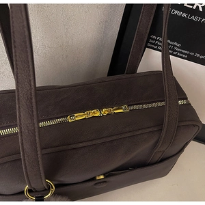 Detail of dark chocolate matte tote with golden dual metal zippers and texture