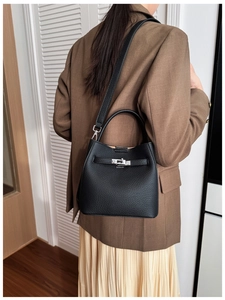 Detail of black lychee grain leather bucket bag with silver metal twist lock and handle