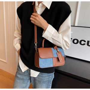 Detalle de bolso baguette en cuero marrón y denim azul llevado por una modelo real