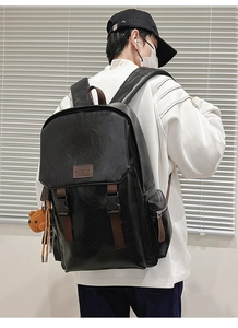 Detail of the black PU leather backpack with brown straps and a cute teddy bear pendant