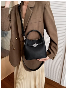 Detail of black pebbled leather bucket bag featuring a silver metal turn-lock closure