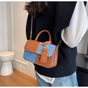 Detail of a brown leather and blue denim crossbody bag shown on a model's back