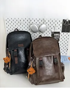 Close-up of black and brown vintage faux leather backpacks with buckle detail and plush charm