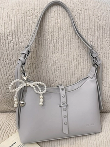 Light gray leather dumpling bag with pearl bow and silver rivets on textured background