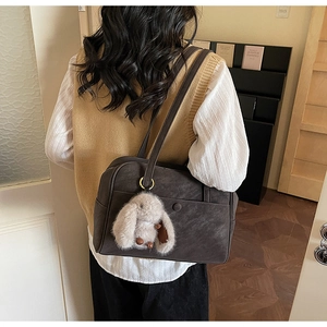 Detail of dark brown vintage tote bag with soft texture and cute white rabbit charm