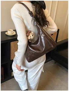 Vue macro du sac hobo en cuir marron foncé avec sangle à nœud et pendentif ours