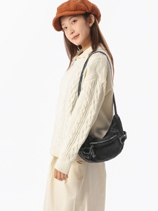 Sac bandoulière demi-lune noir en cuir mat porté par un mannequin dans un studio