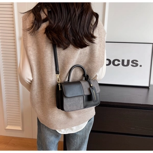 Detail of color-block flap bag showing gray texture, gold hardware and leather handle