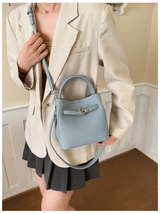 Detail of light blue lychee pattern leather bucket bag with metal buckle and shoulder strap
